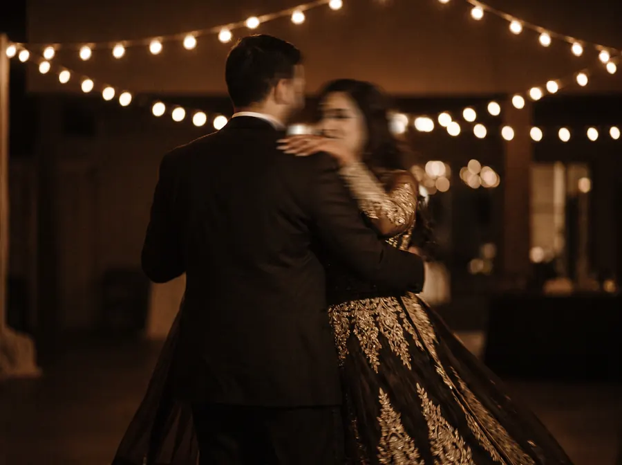 Film-style still of a couple's first dance under string lights