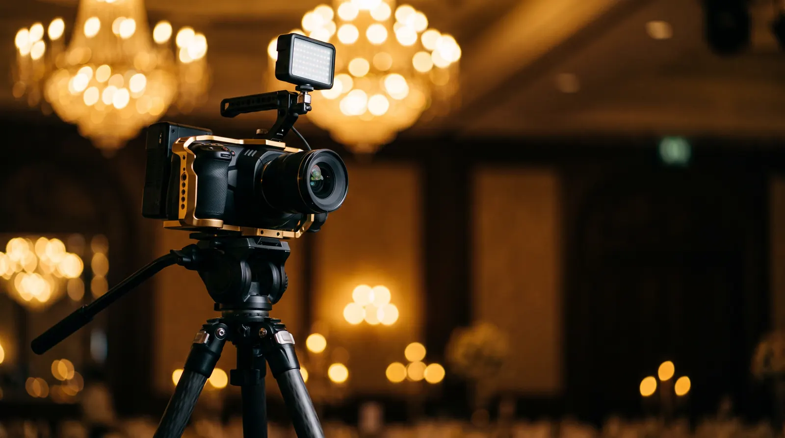 Professional cinema video camera on a tripod with warm chandelier bokeh in the background
